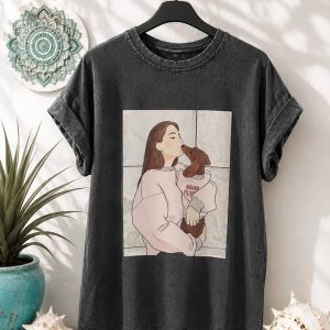 Camiseta gris oscuro de manga corta con efecto lavado e ilustración central de una mujer abrazando a un perro salchicha.