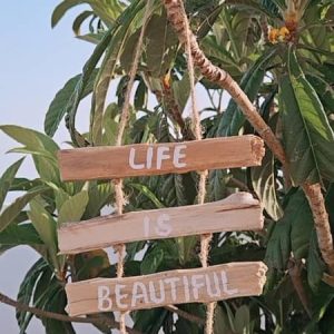 Móvil colgante artesanal de madera hecho en Indonesia con la frase Life is Beautiful y un corazón pintados a mano,