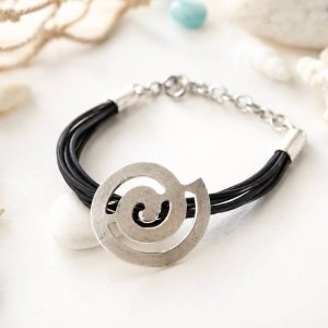 Pulsera artesanal de hilos de caucho negro con un gran dije central en forma de espiral de zamak plateado