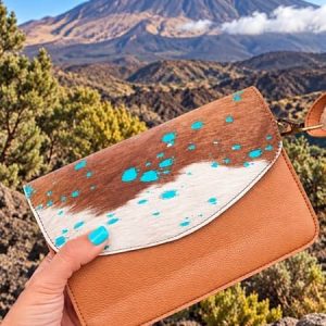 Bolso de cuero artesanal marrón con solapa de estampado animal y detalles turquesas