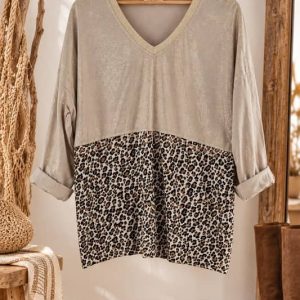 Blusa de manga larga de algodón en color beige con escote en pico dorado y estampado de leopardo en la parte inferior colgada en percha de madera.